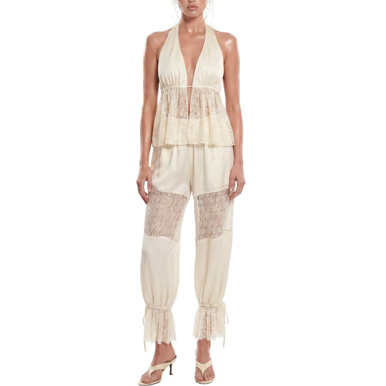 Woman wearing a cream-colored lace jumpsuit on a white background