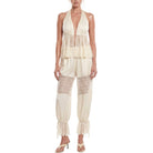 Woman wearing a cream-colored lace jumpsuit on a white background