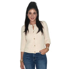A woman modeling a cream-colored, textured three-quarter sleeve cardigan with gold buttons, paired with blue jeans, against a plain white background.