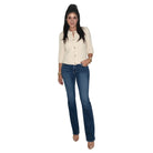 A woman modeling a cream-colored, three-quarter sleeve button-up cardigan with gold buttons, paired with dark blue jeans and beige heels, set against a plain white background.