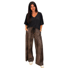 A woman modeling a black short-sleeve V-neck top with brown textured drawstring pants against a plain white background.