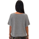 A woman viewed from the back wearing a short-sleeve, loose-fit gray top, shown against a plain white background.