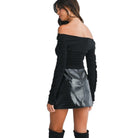 Woman wearing a black off-shoulder top and black leather skirt on a white background