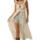 Woman wearing a white lace cover-up and denim shorts on a white background