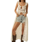 Woman wearing a white lace top, denim shorts, and brown boots on a white background