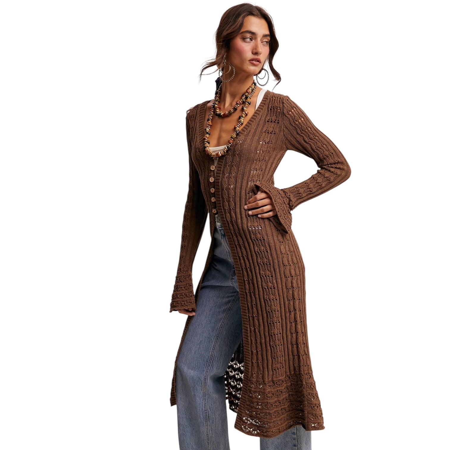 Woman wearing a brown ribbed cardigan over a beige top and blue jeans on a white background