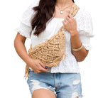 Person holding a woven beige bag against a white background