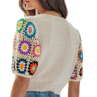 Beige knit cardigan with colorful floral patterns on sleeves and back against a white background