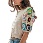 Woman wearing a colorful crochet cardigan with a white background
