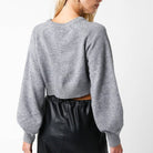 Person wearing a gray sweater and black pants on a white background