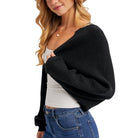 Woman wearing a black cardigan over a white top and blue jeans on a white background