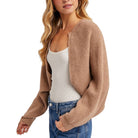 Woman wearing a brown cardigan over a white top and blue jeans on a white background