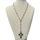 A long gold-tone lariat-style necklace with dark blue and white gemstone accents, displayed on a beige fabric jewelry bust against a white background.