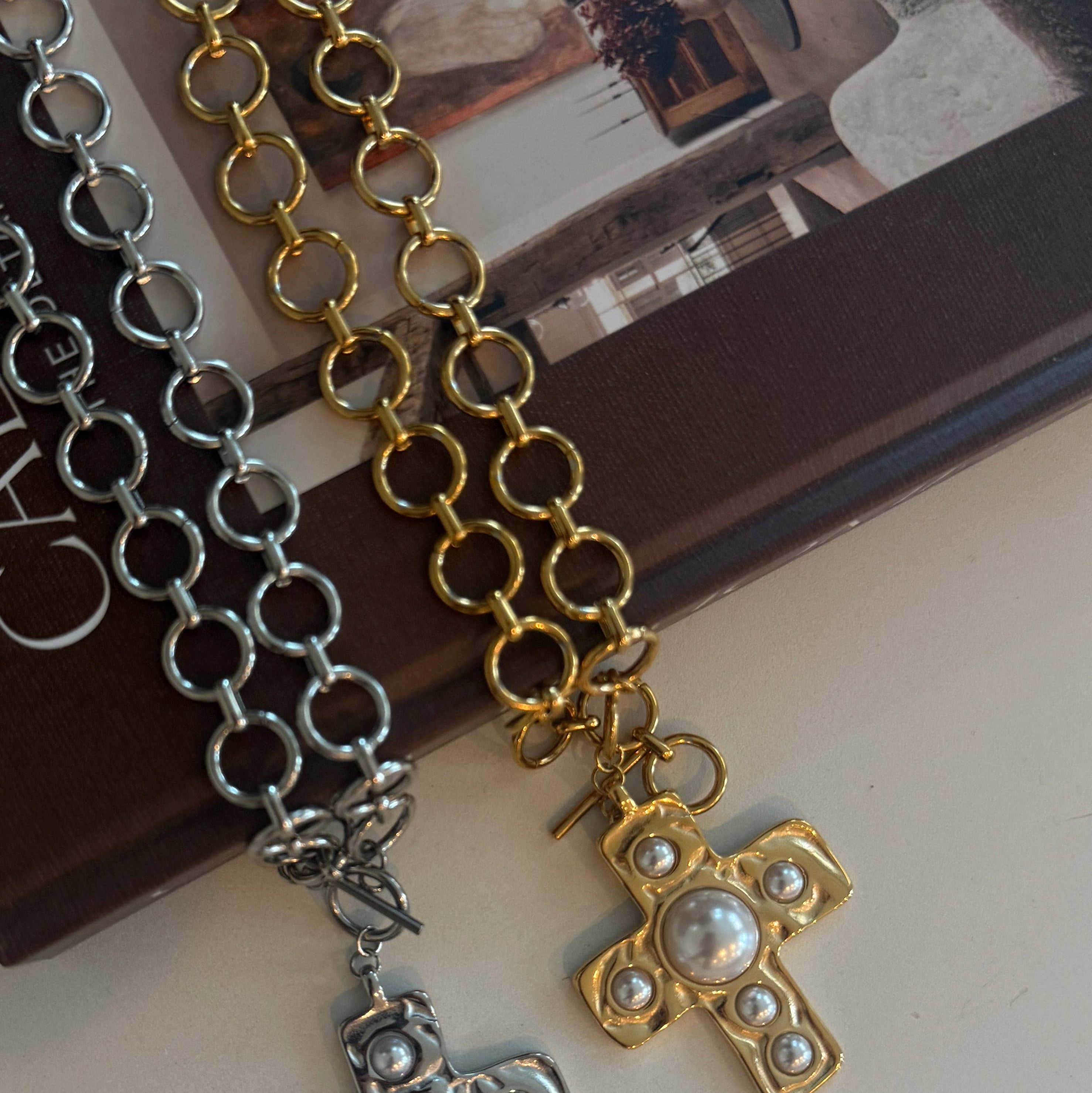 Chain necklaces with cross pendants on a white surface