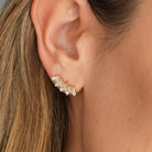 Close-up of an ear wearing a diamond earring with a neutral background