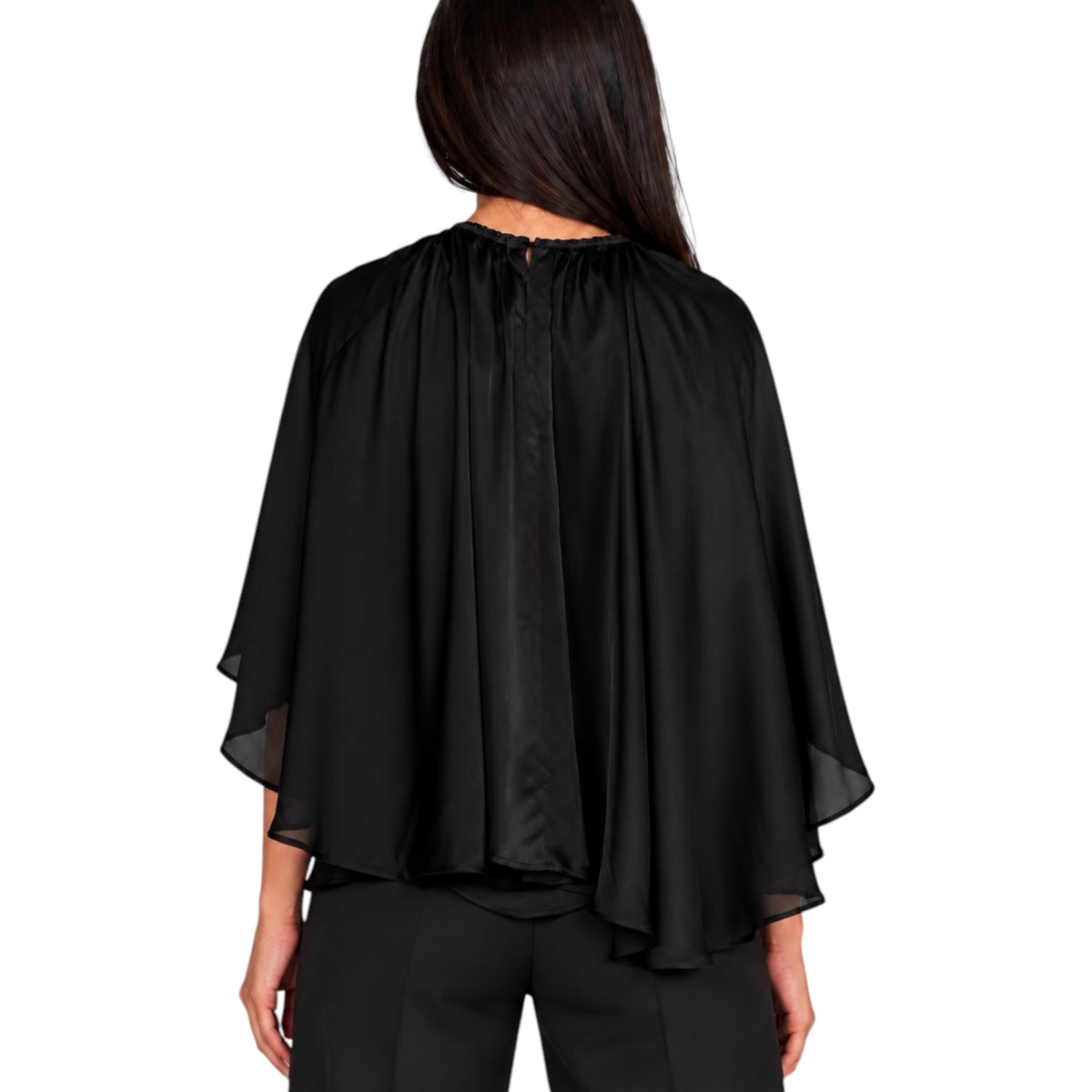 A woman viewed from the back wearing a black draped cape-style top with wide sheer sleeves and black pants, against a plain white studio background.