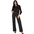 A woman modeling a black two-piece outfit consisting of a short-sleeve blouse with flutter sleeves and keyhole neckline, paired with high-waisted black wide-leg trousers, on a solid white background.