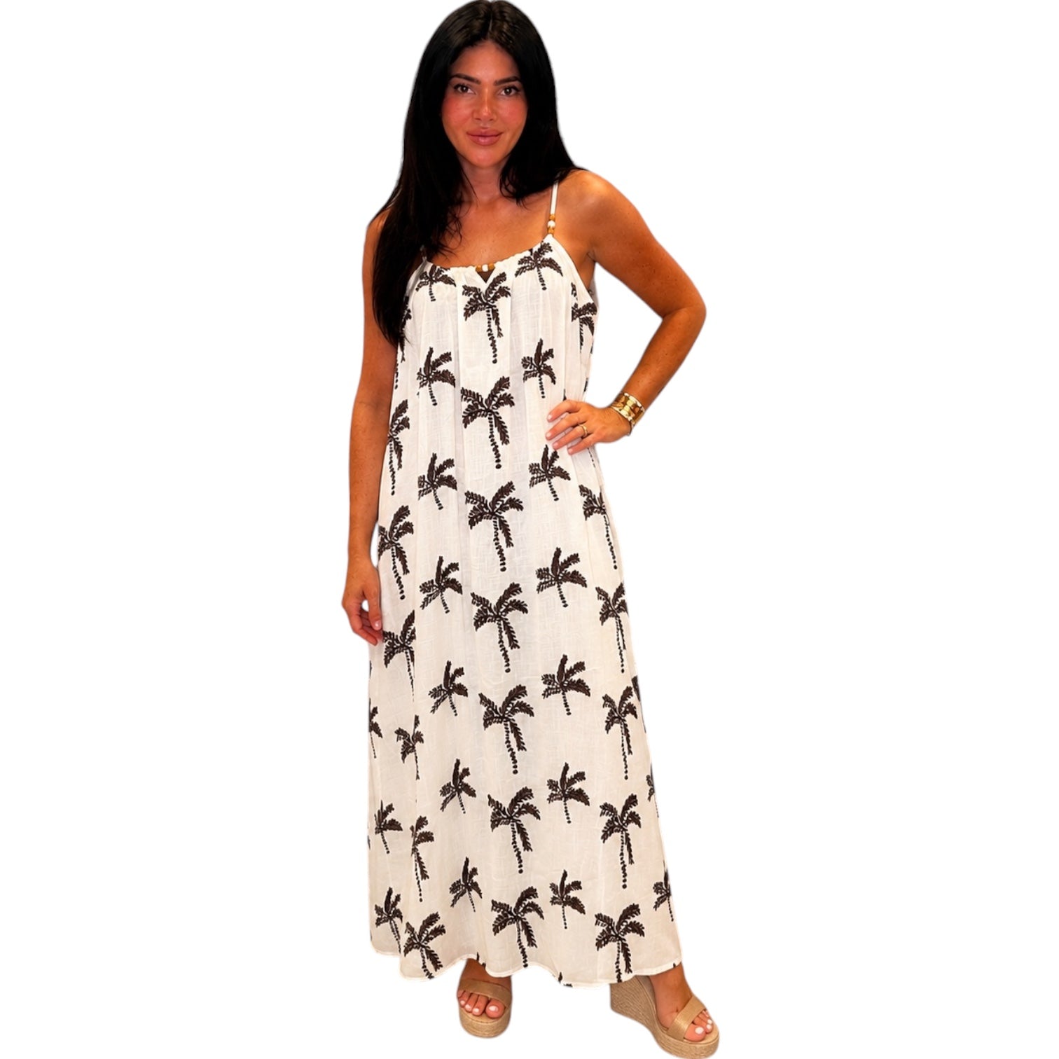 Woman wearing a ivory dress with brown palm tree patterns on a white background
