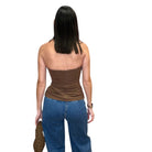 Woman wearing a brown halter top and blue jeans on a white background
