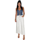 woman wearing denim lace-up corset top with white jeans on white background