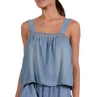 Woman wearing a blue denim top with lace trim on a white background