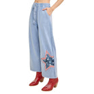 Light blue denim pants with a star patch worn by a person on a white background