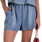 Person wearing blue denim shorts with a plain background
