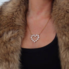 Heart-shaped necklace worn by a person in a fur coat