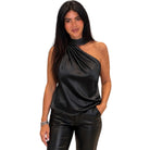 A woman modeling a black satin-like one-shoulder top with a matching black faux-leather pants set against a plain white background.