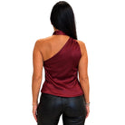 A woman shown from the back wearing a satin-like one-shoulder top in deep burgundy and black faux-leather pants, against a plain white background.
