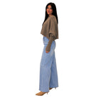 A woman modeling a taupe-brown knit cropped sweater with balloon sleeves and light-wash wide-leg denim jeans, shown from the back against a plain white background.