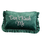 A dark green velvet clutch pouch with ruffled trim on all sides, featuring the phrase 'Don't Rush Me' embroidered in light pink script across the front.