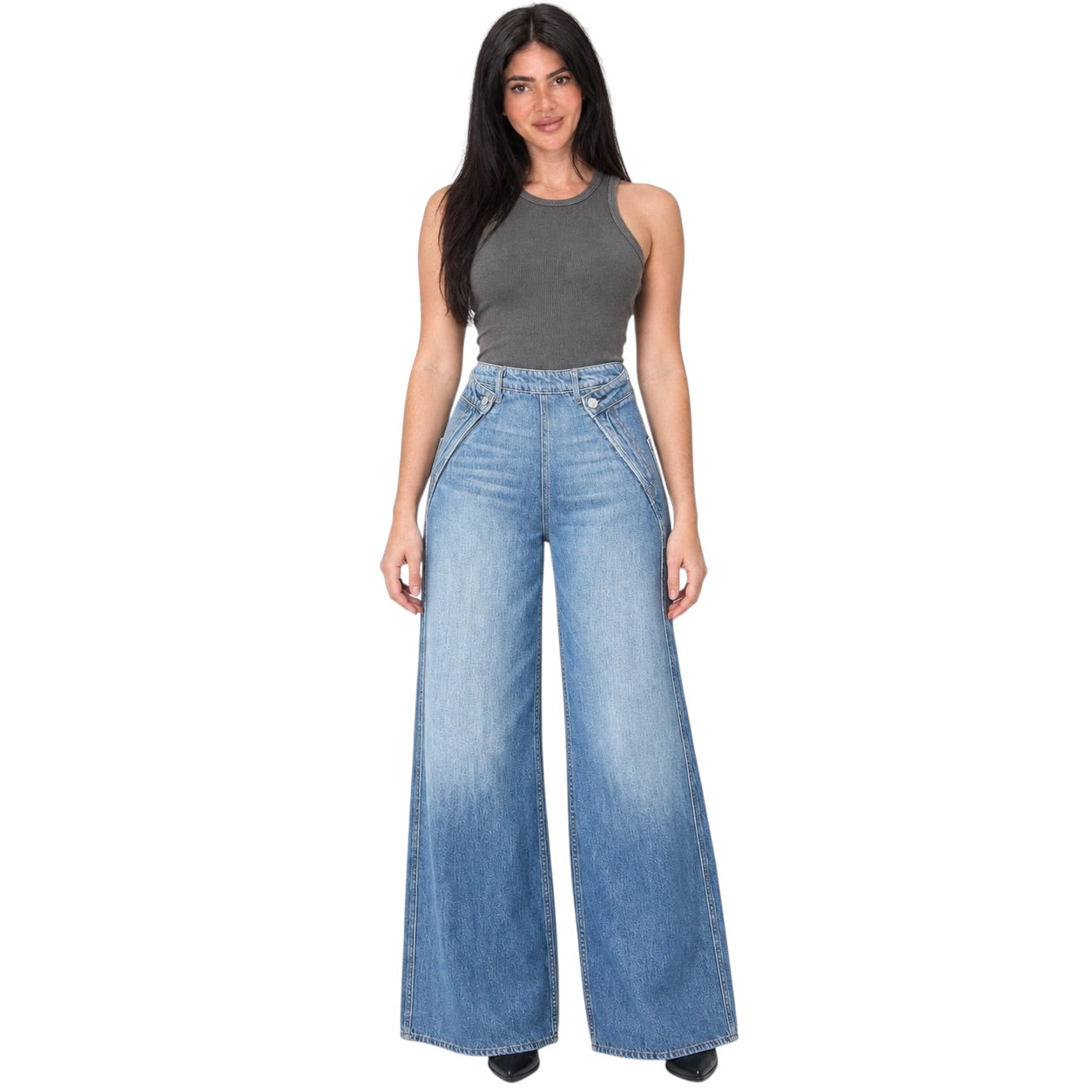 A woman modeling a pair of wide-leg light blue denim jeans with a faded wash, paired with a dark gray sleeveless top, against a plain white background.
