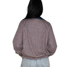 A person shown from the back wearing a long-sleeve checkered bomber jacket with a dark navy collar and light blue jeans, against a plain white background.