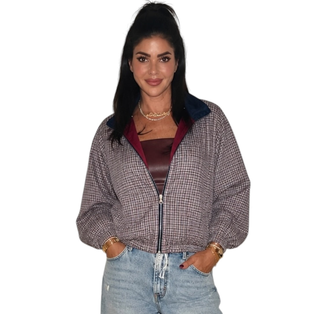 A woman modeling a cropped zip-up jacket with a gray and white micro-check pattern, a dark navy collar, and a burgundy lining, paired with light-wash distressed jeans.