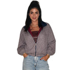 A woman modeling a cropped zip-up jacket with a gray and white micro-check pattern, a dark navy collar, and a burgundy lining, paired with light-wash distressed jeans.