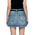 Person wearing a blue denim skirt with a black belt on a white background