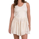 Woman wearing a white sleeveless dress with a layered skirt on a white background
