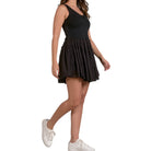 Woman wearing a black dress and white sneakers on a white background