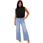 A woman modeling a sleeveless black top and light-wash wide-leg denim jeans against a plain white background.