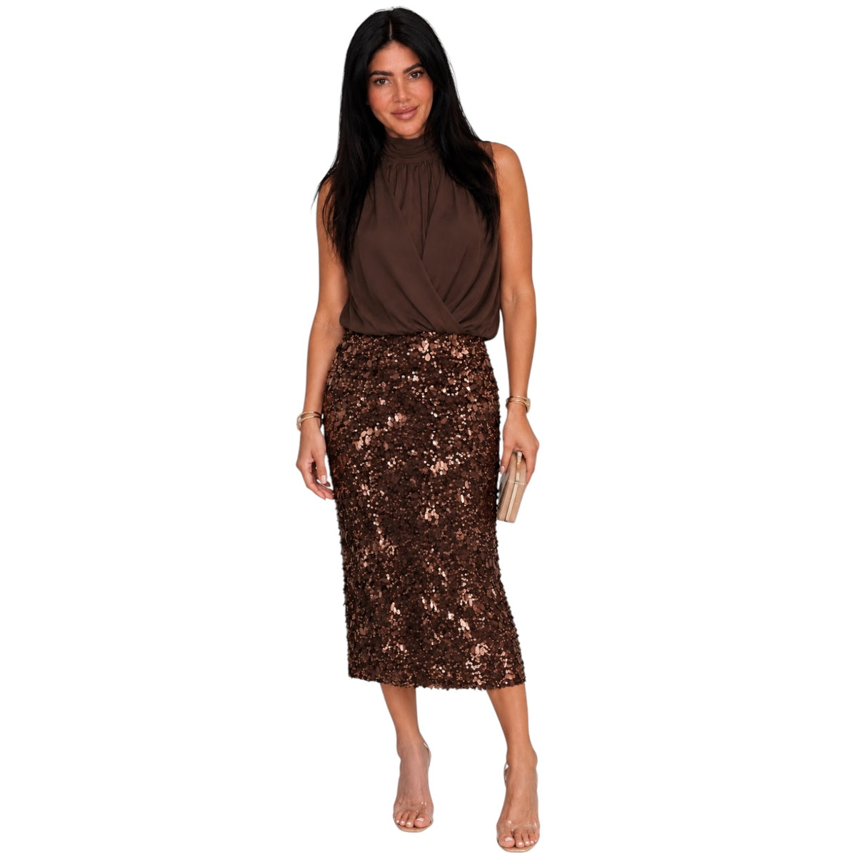 A woman modeling a sleeveless high-neck brown top and a brown sequined midi skirt, holding a small metallic clutch against a plain white background.