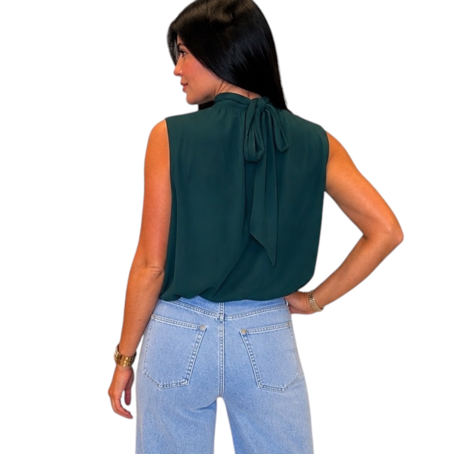 A woman shown from the back wearing a sleeveless dark green blouse with a tie-neck detail and light blue jeans, against a plain white background.