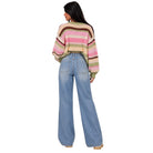 A woman shown from the back wearing a pastel striped knit sweater with wide-leg light blue jeans, photographed against a plain white studio background.