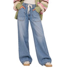 A person wearing light-wash wide-leg denim jeans with a white drawstring waist, styled with a striped knit cardigan and beige shoes against a plain white background.