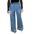 Person wearing a black top and blue wide-leg jeans on a white background