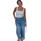 Woman wearing a gray tank top and blue jeans on a white background