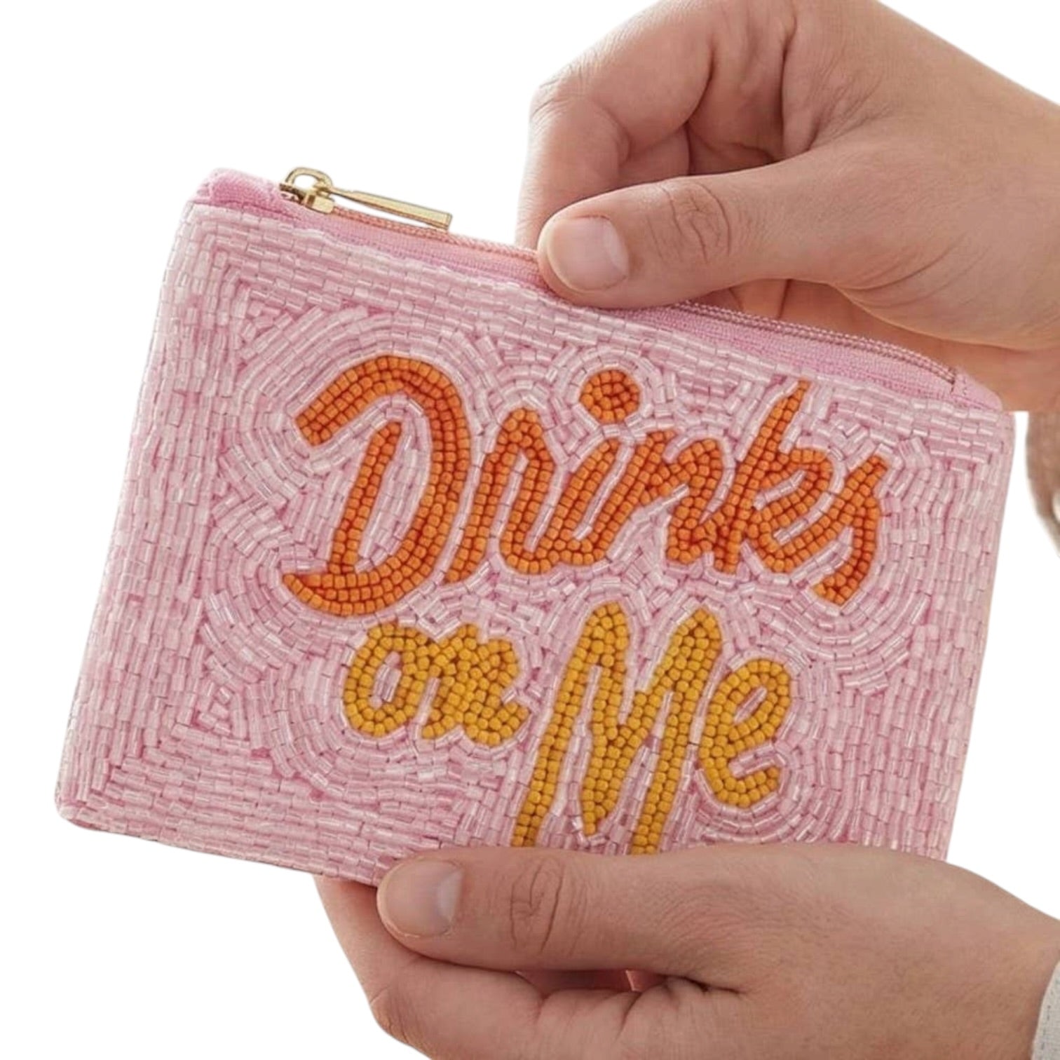 Pink beaded pouch with 'Drinks on Me' text held by a hand against a white background