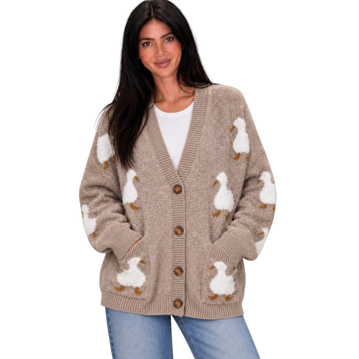 A woman wearing a beige knit cardigan with white and brown duck motifs, styled over a white top and blue jeans against a plain white background.