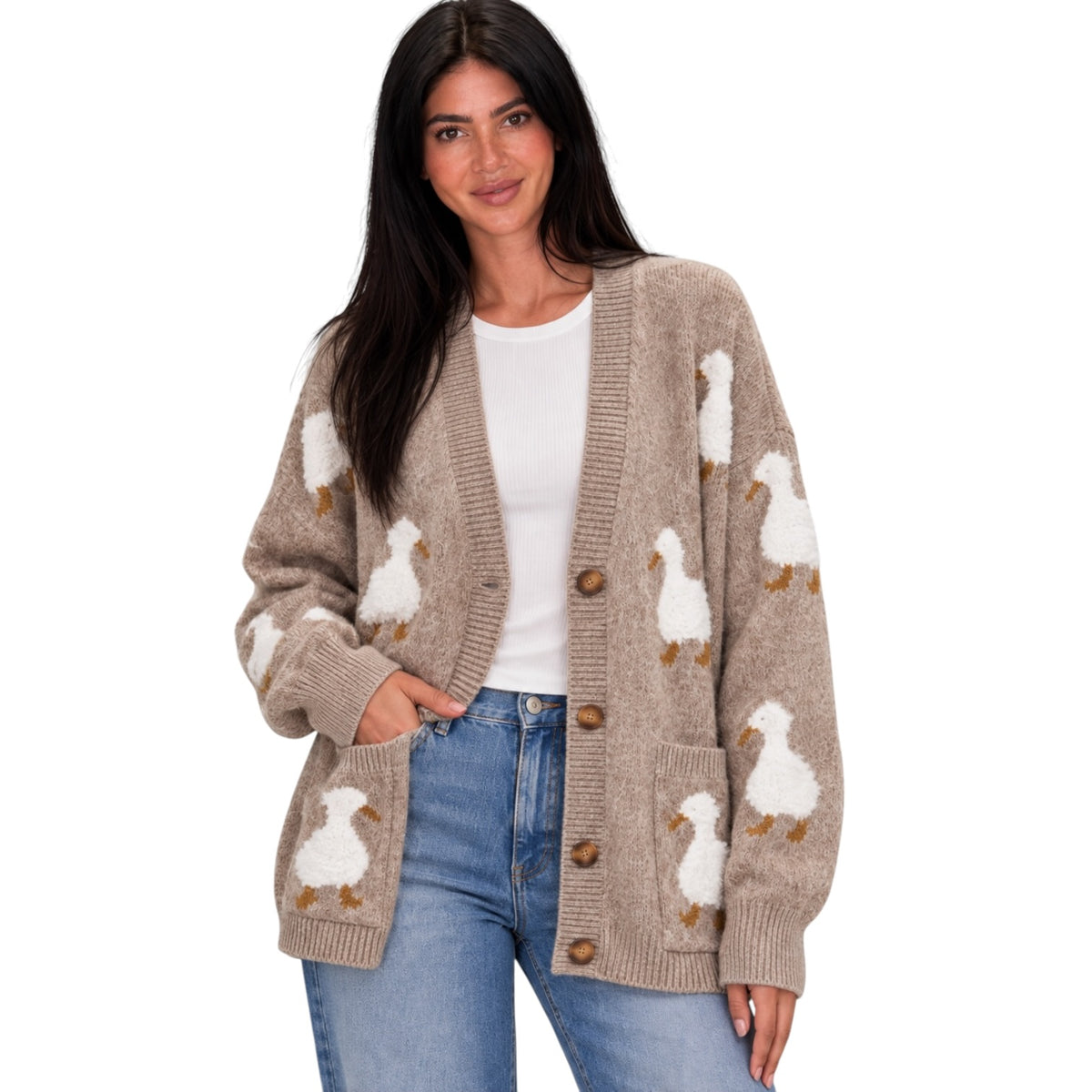 A woman wearing a beige knit cardigan with white duck motifs and brown buttons, styled over a white top and blue jeans against a plain white background.