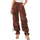 A model wearing high-waisted, wide-leg brown cargo pants made of a shiny satin-like fabric, styled with a white top and beige high-heeled sandals against a plain white background.